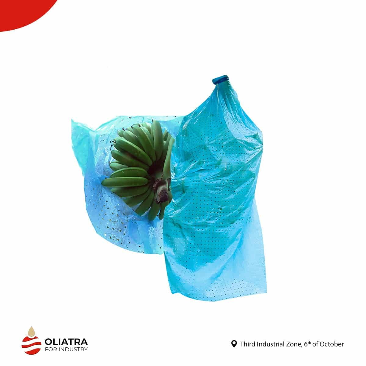 Banana Bags 1 A bunch of green bananas peeks out from a torn blue أكياس بولى إيثيلين.